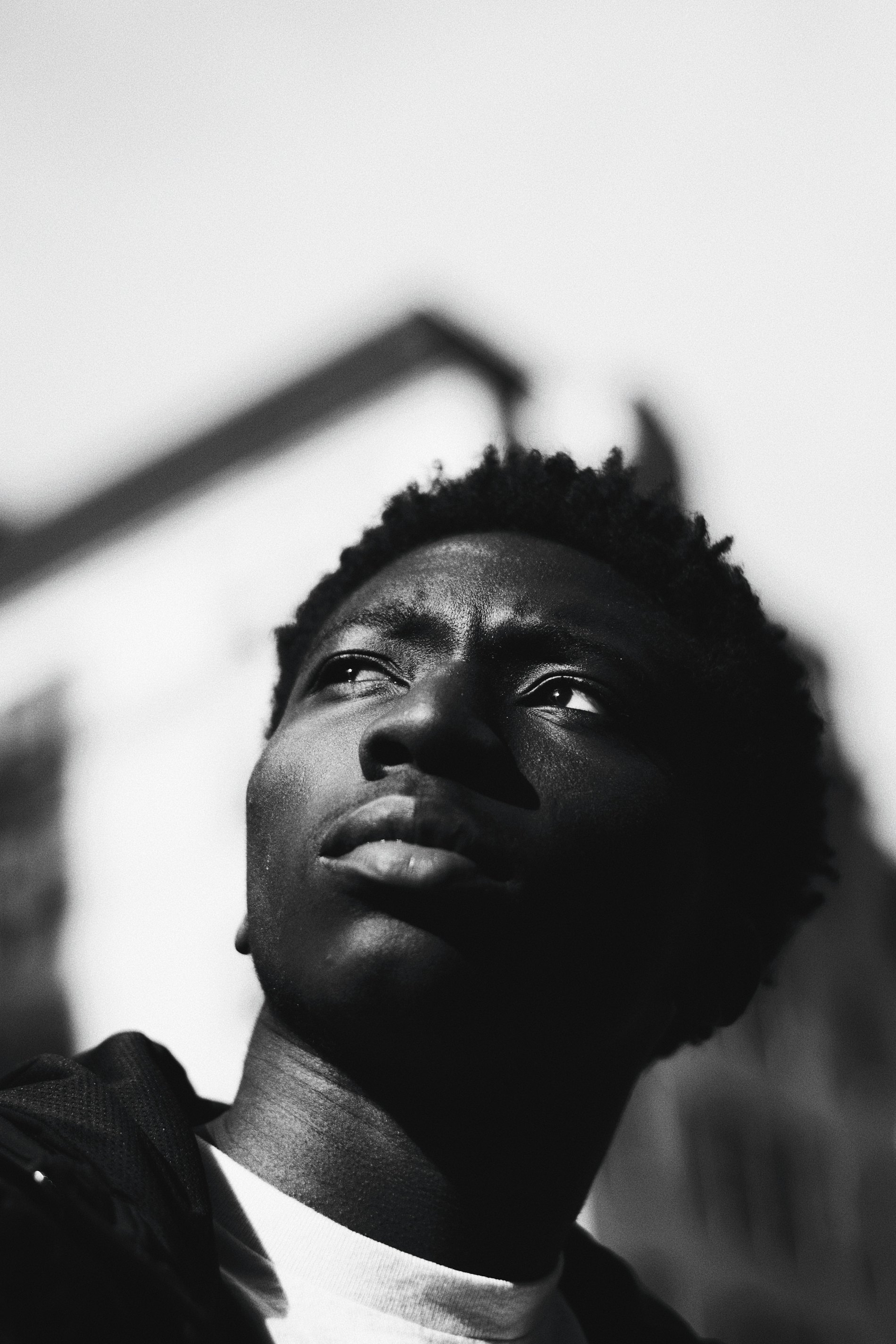 A young Black man lit from above, looking upward with resolve